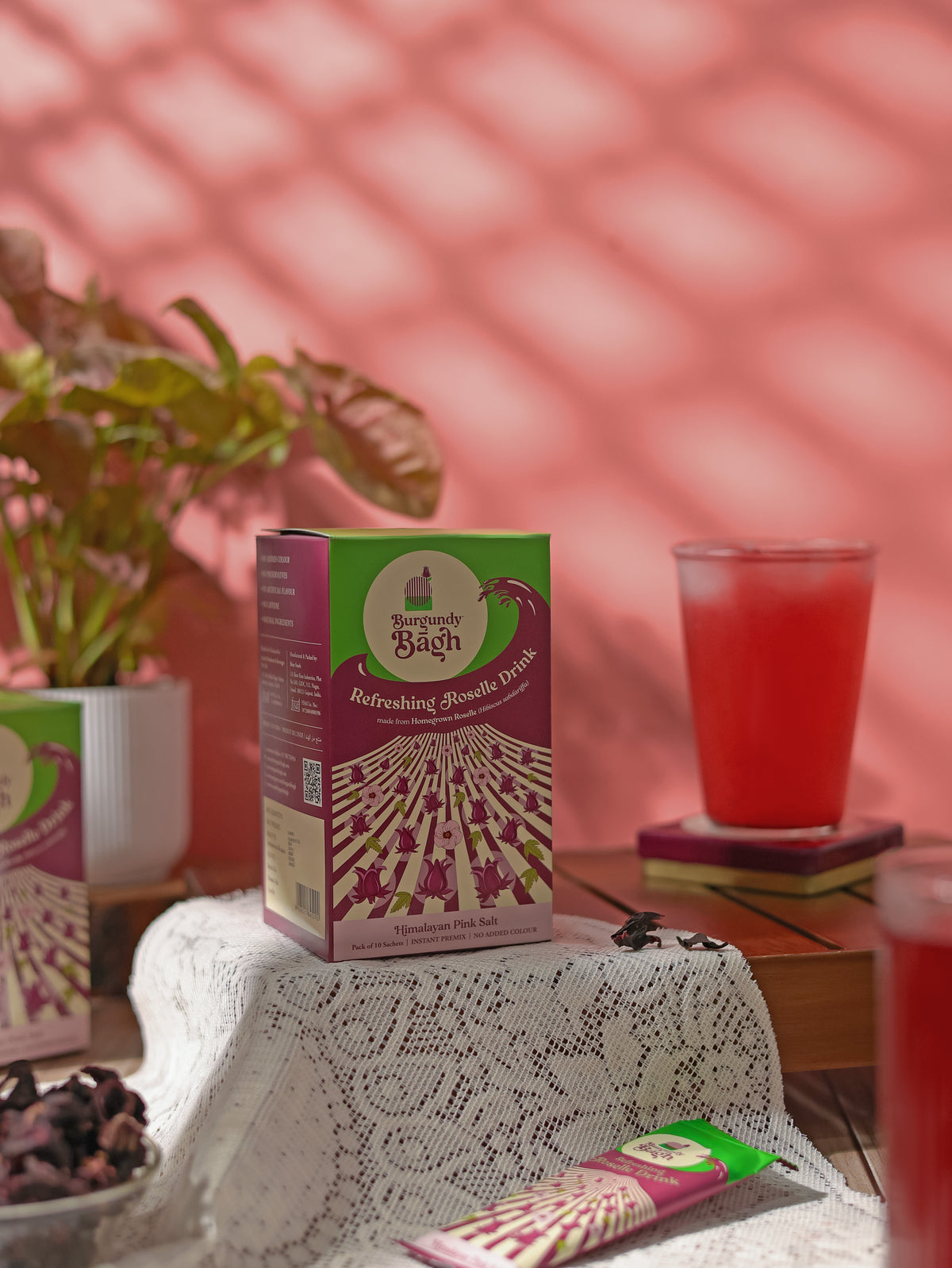 Burgundy Bagh Refreshing Roselle Drink pre-mix pack beside a chilled glass