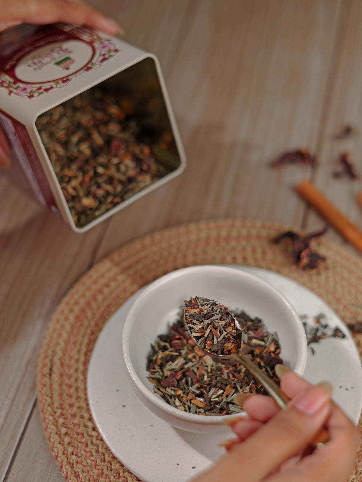 Spooning whole leaf roselle tea from a Burgundy Bagh tin into a bowl