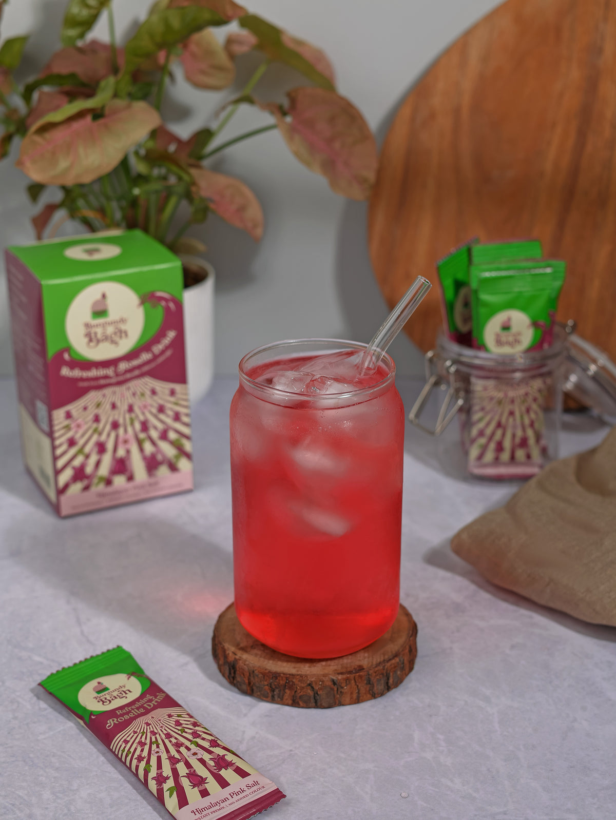 Burgundy Bagh Refreshing Roselle Drink pre-mix pack beside a chilled glass of roselle over ice