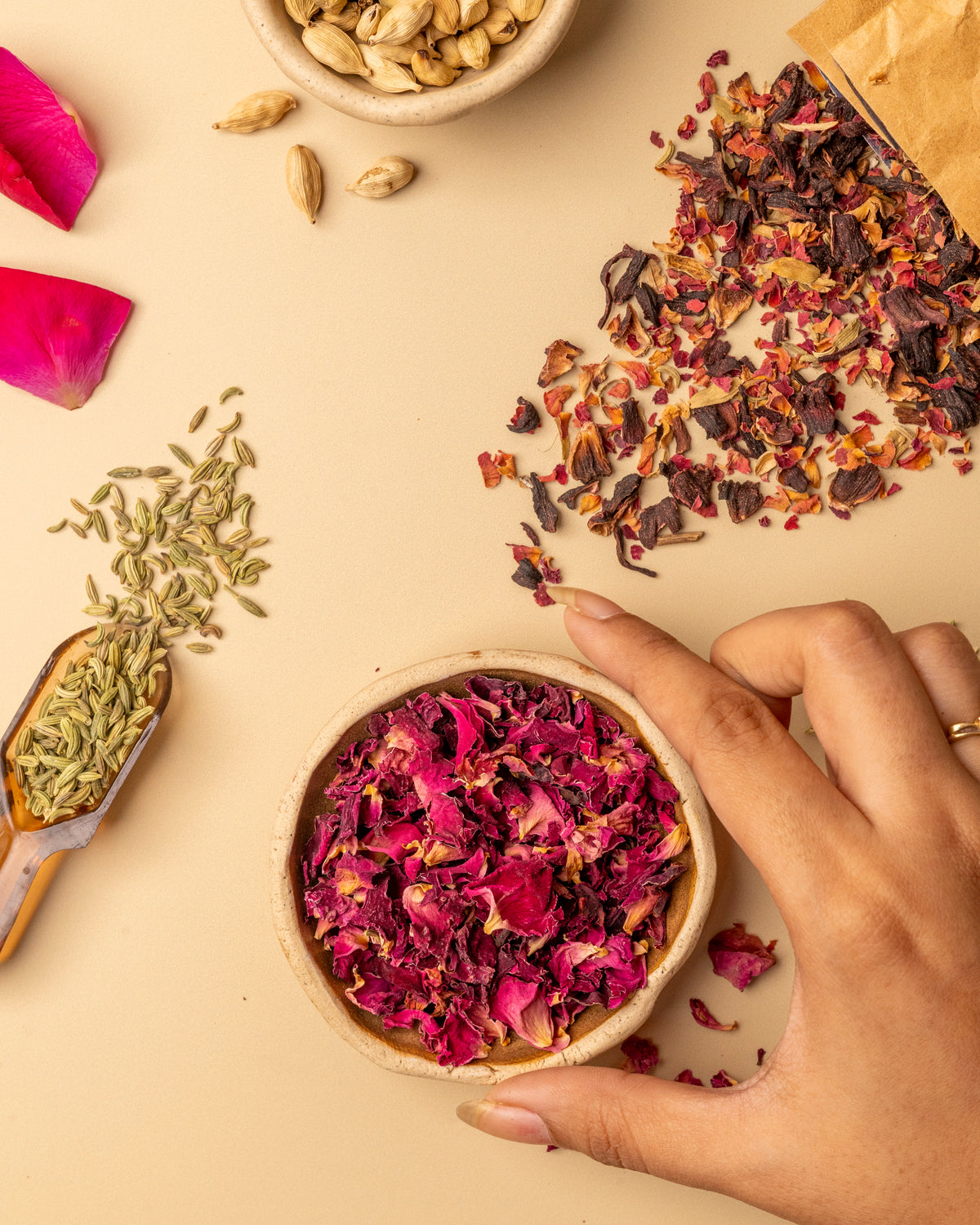 Dried rose petals and roselle in a bowl, held by hand